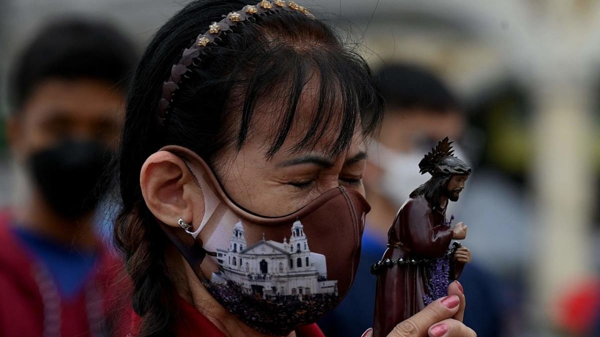 A devotee holds a statue of Jesus Christ as she prays outside the Quiapo Church in Manila on December 28, 2022, ahead of the Feast Day of the Black Nazarene. Credit: AFP Photo