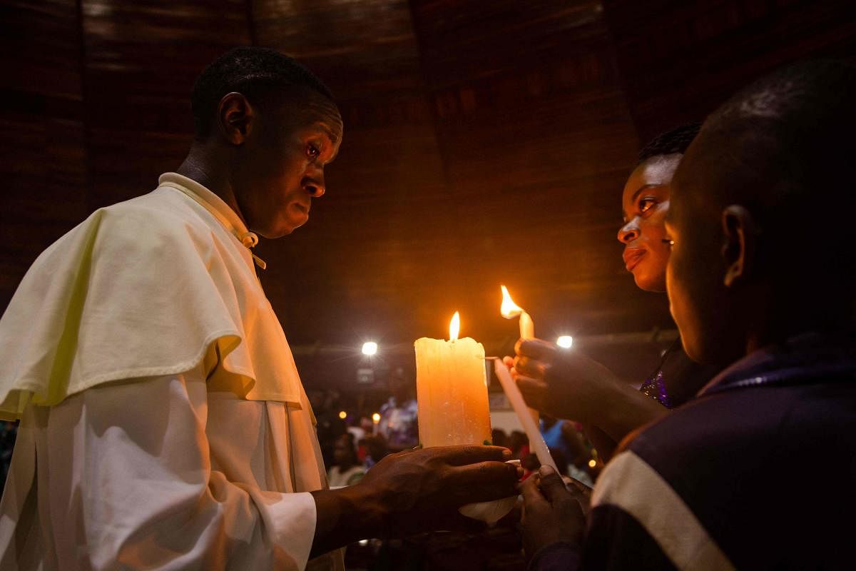 Catholic faithfuls light candles inside the Basilica of the Uganda Martyrs to pray after receiving news about the death of former Pope Emeritus Benedict XVI in Namugongo, Kampala, Uganda. Credit: AFP Photo