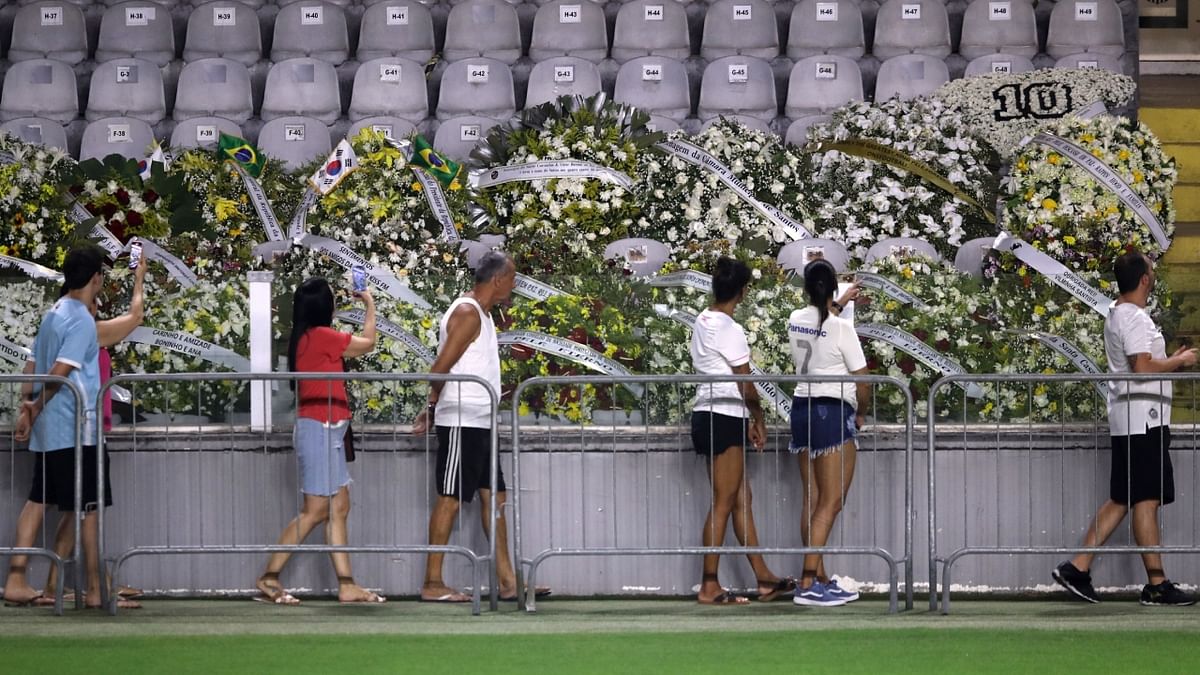 Mourners walk past floral tributes as they queue to pay their respects at Santos' Vila Belmiro stadium. Credit: Reuters Photo