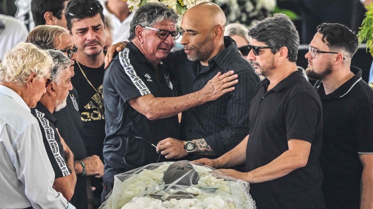Former Santos player Manoel Maria hugs Edinho during the funeral. Credit: AFP Photo