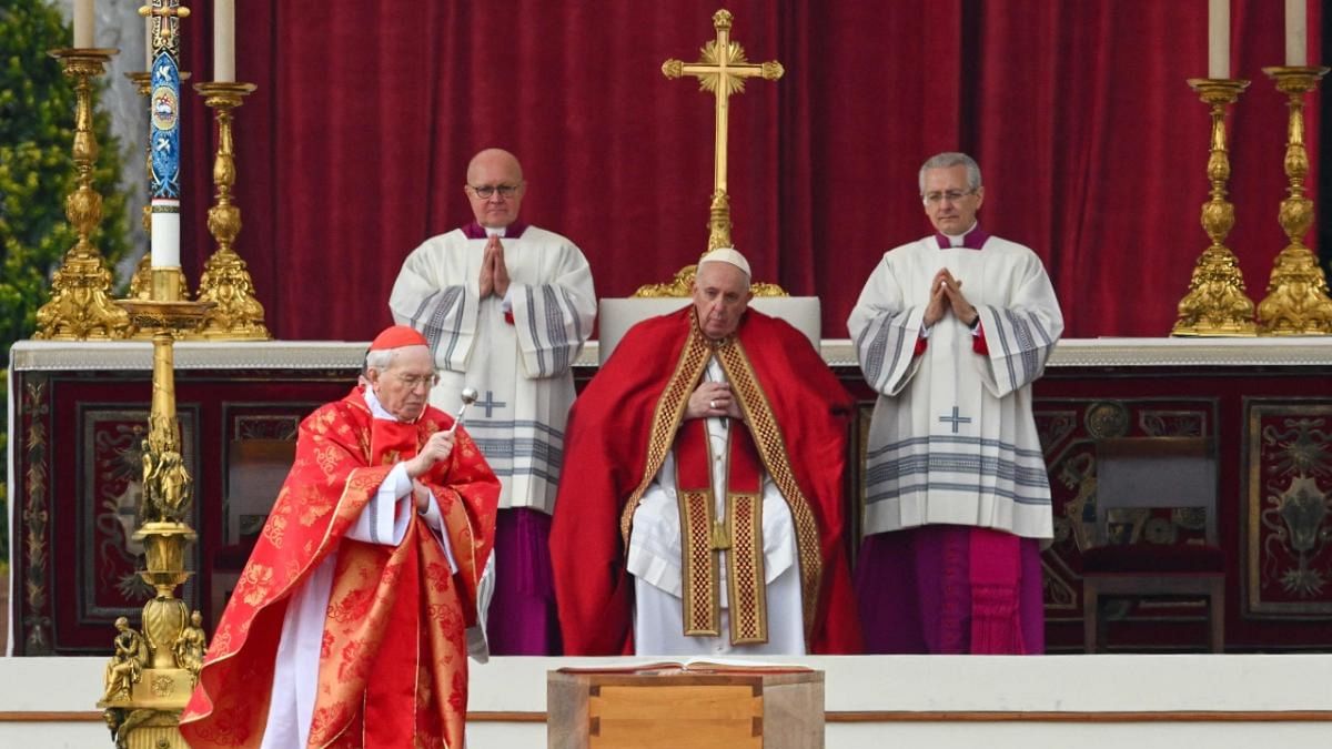 Italian Cardinal Giovanni Battista Re (L) blesses the coffin of Pope Emeritus Benedict XVI, as Pope Francis looks on (C) during his funeral mass at St. Peter's square in the Vatican on January 5, 2023. Credit: AFP Photo
