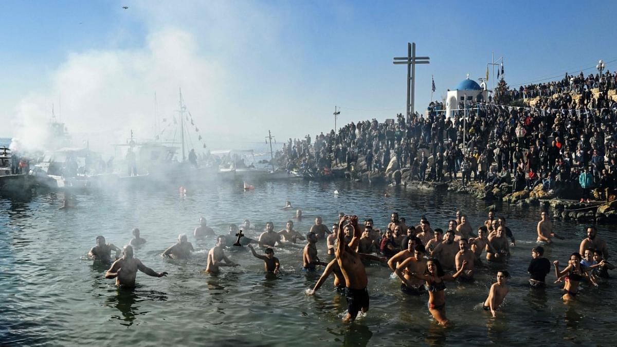 Greek Orthodox believers try to catch a wooden cross thrown by a priest into the sea, during the traditional blessing of water for the Orthodox Epiphany Day, in Piraeus near Athens on January 6, 2023. Credit: AFP Photo