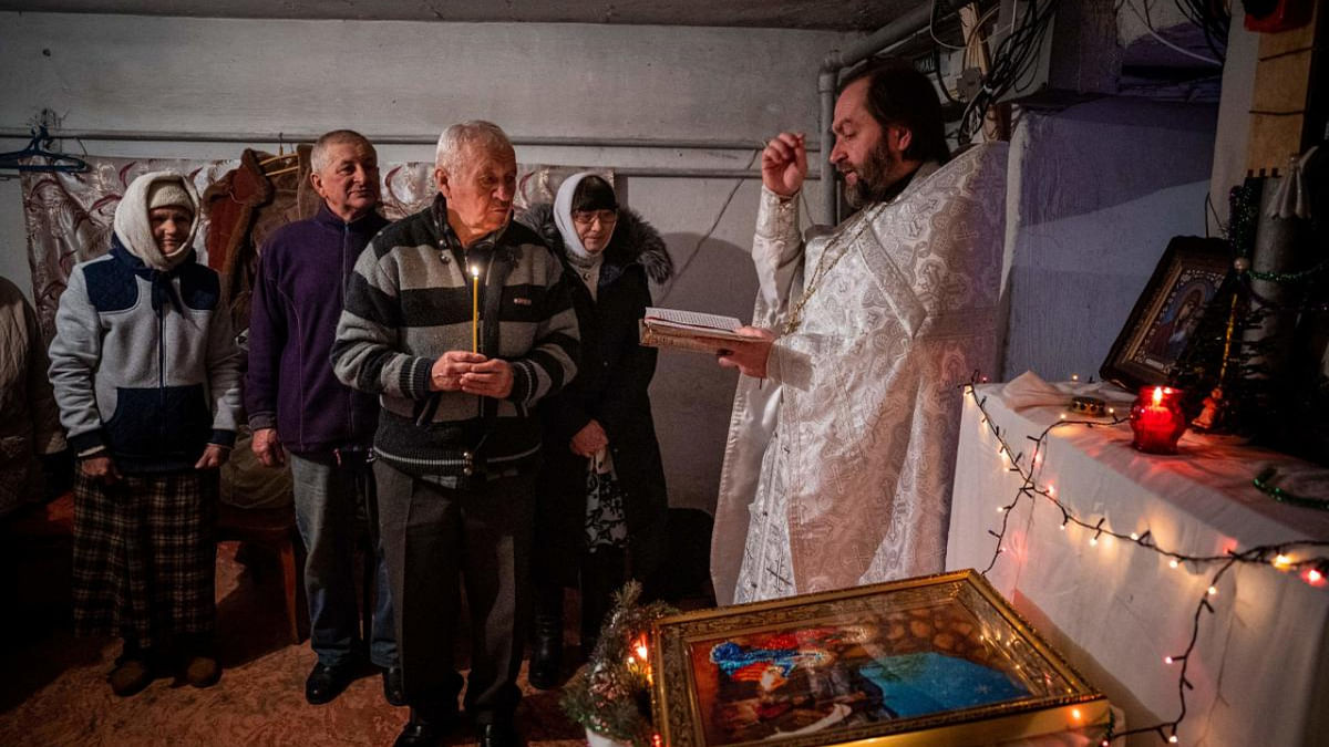 A priest leads an Orthodox Christmas mass in a basement shelter in Chasiv Yar, Eastern Ukraine. Credit: AFP Photo