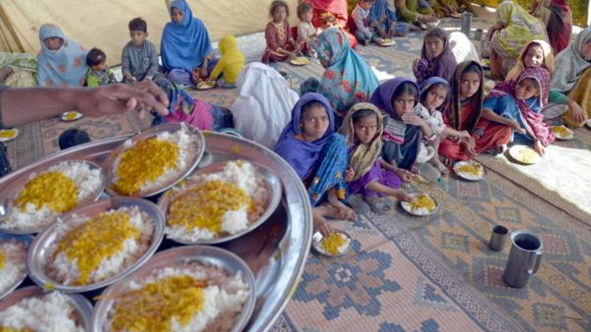 Internally displaced flood-affected people eat free food provided by Bahria Dastarkhwan, a charitable organisation near a makeshift camp in the flood-hit area of Dera Allah Yar in Jaffarabad district of Balochistan. Credit: AFP Photo