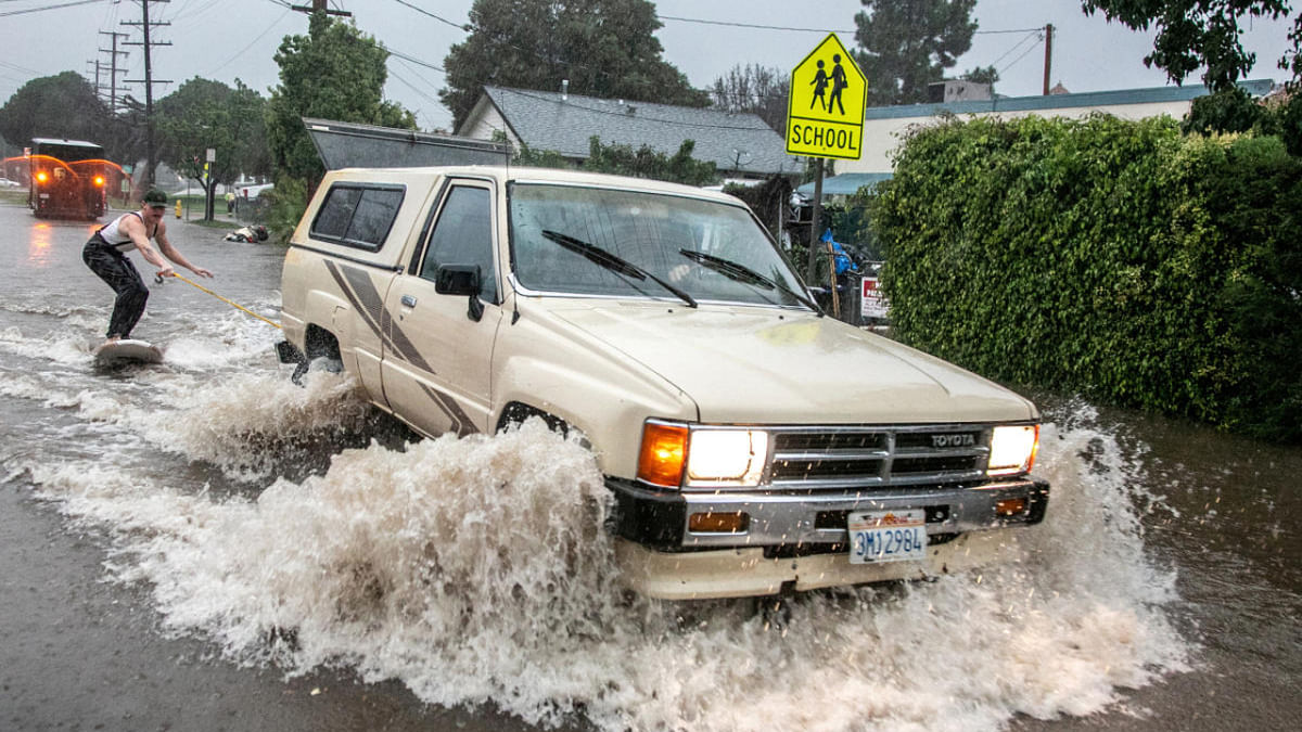 Max Barnett, 23, is pulled on a surfboard by driver Riley Johnson, 23, down a flooded street after the threat of mudslides prompted evacuation orders in east Santa Barbara, California. Credit: Reuters Photo