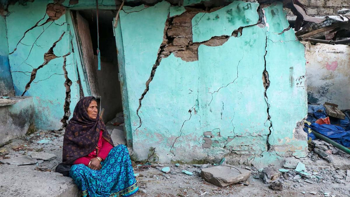 A woman sits beside a cracked wall of her house at Joshimath in Chamoli district of Uttarakhand. Credit: AFP Photo Afghan girls stand outside their house in Sangin district of Helmand province. Credit: AFP Photo