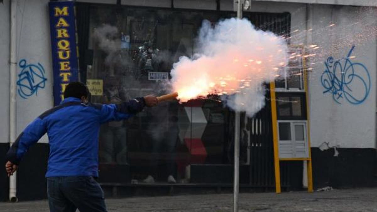 A supporter of the ruling Movement To Socialism (MAS) fires a petard to opposers to President Luis Arce during a protest march