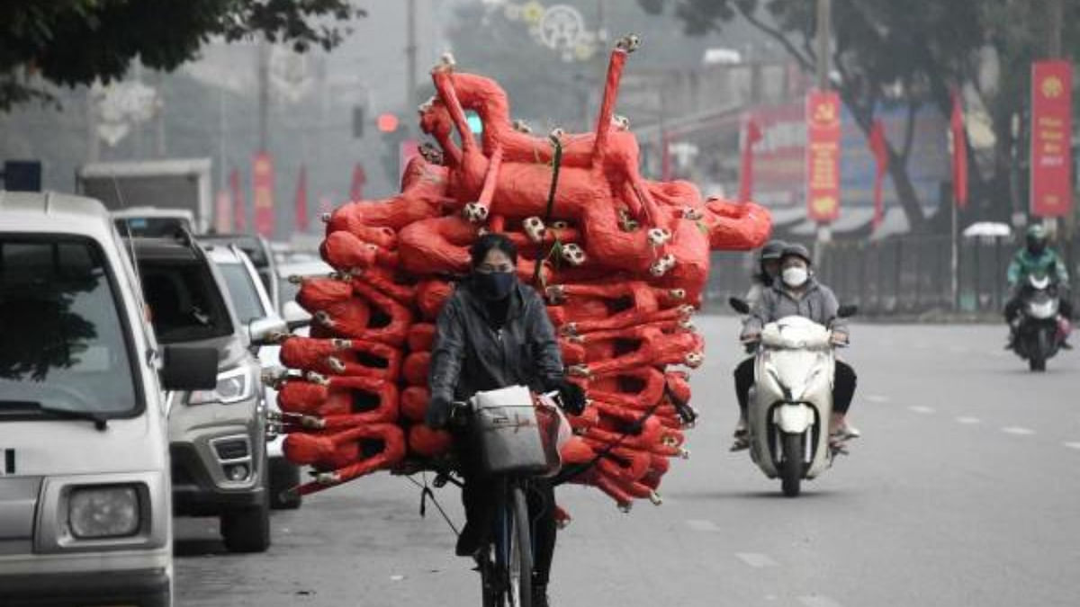 A woman carries horse figurines, to be used as offerings at religious ceremonies, on her bicycle as she transports them to shops for sale in Hanoi. Credit: AFP Photo