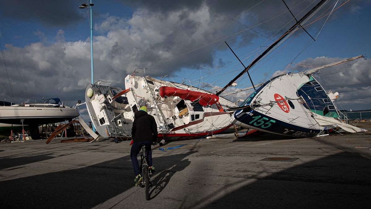 A man rides his bicycle past Class 40 ships layed on the ground at the Chantereyne port, in Cherbourg, northwestern France, on January 16, 2023, after the storm 'Gerard' hit the region. Credit: AFP Photo