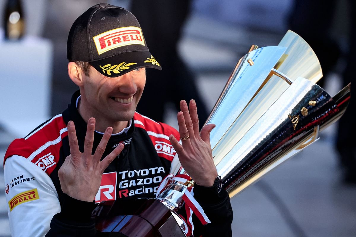 French driver Sebastien Ogier shows the number nine with his fingers, holding his trophy as he celebrates his victory after winning the 91st WRC Monte-Carlo Rally. Credit: AFP Photo