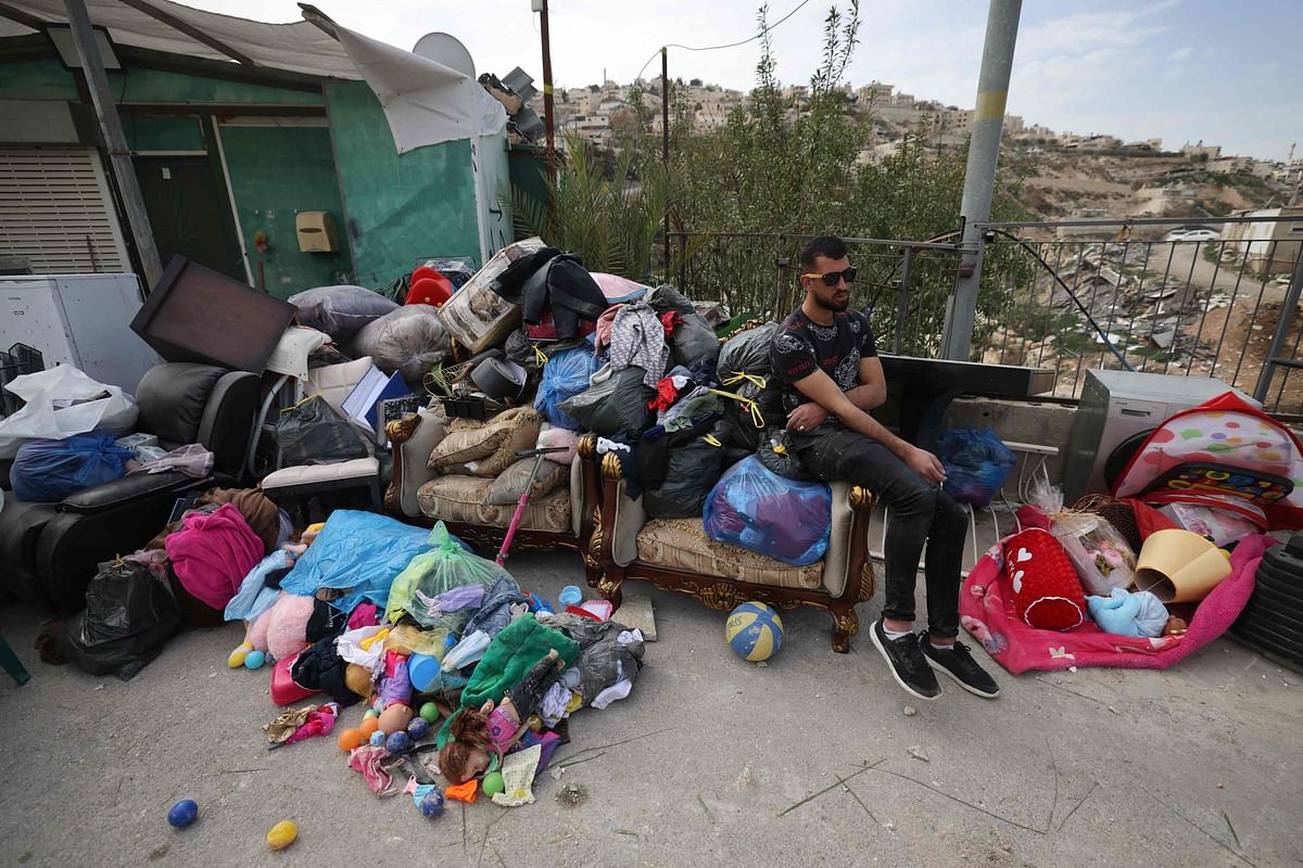 A Palestinian man sits next to the belongings of Rateb Hatab Shukairat, after the house was demolished by Israeli bulldozers, in the East Jerusalem neighbourhood of Jabal Mukaber on January 29, 2023. Credit: AFP Photo