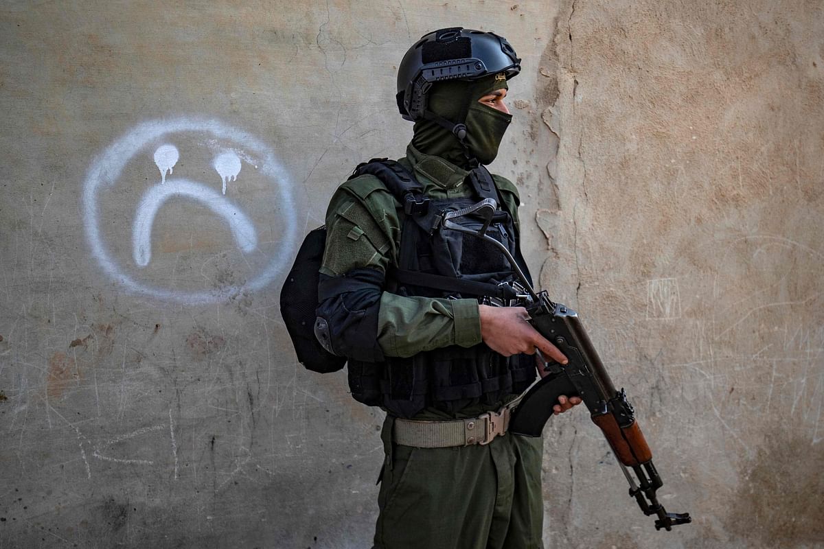 A member of the Syrian Kurdish Asayish security forces walks past a house during a raid against suspected Islamic State group fighters in Raqa. Credit: AFP Photo