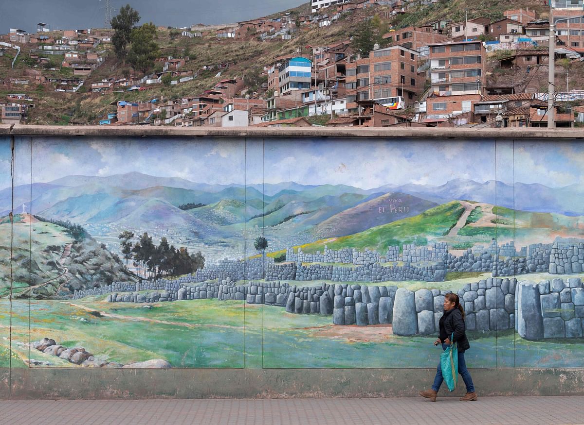 A woman walks next to a mural of the Sacsahuaman Inca fortress in the city of Cusco, Peru, on January 29, 2023, as the number of tourists arriving to the popular tourist destination continues to diminish due to the ongoing nationwide protests. - Violent clashes with police in protests to oust the government of Peruvian President Dina Boluarte, close congress, and call for general elections have already left 48 people dead -among them a policeman. Credit: AFP Photo