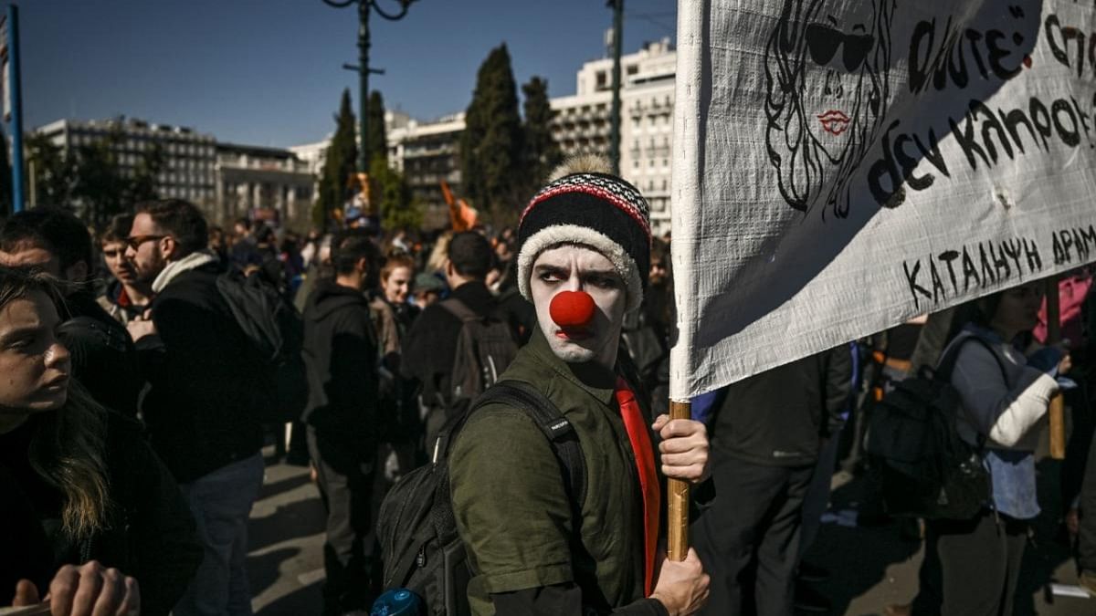 An artist wearing a clown nose holds a banner during a demonstration in front of the Greek parliament in Athens. Credit: AFP Photo
