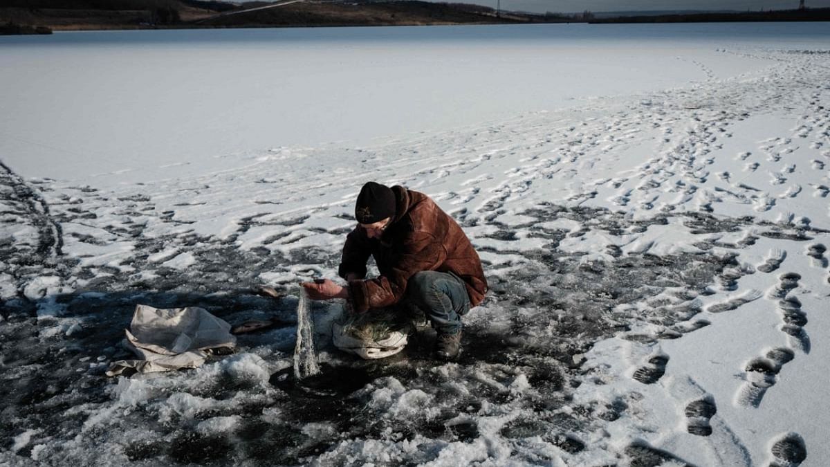 Ukranian Oleksiy pulls the fishing net from a frozen lake near Kramatorsk. Credit: AFP Photo