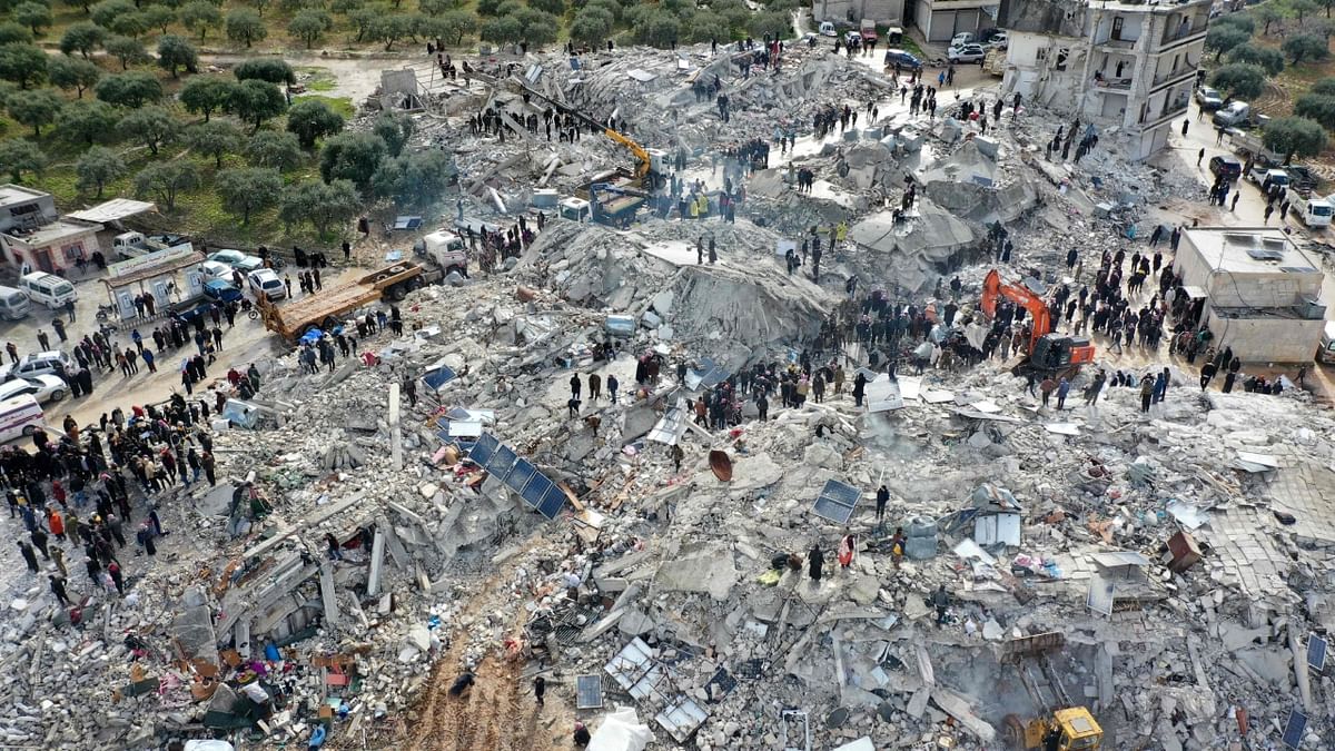 Aerial picture shows residents searching for victims and survivors amidst the rubble of collapsed buildings following an earthquake in the village of Besnia near the town of Harim, in Syria. Credit: AFP Photo