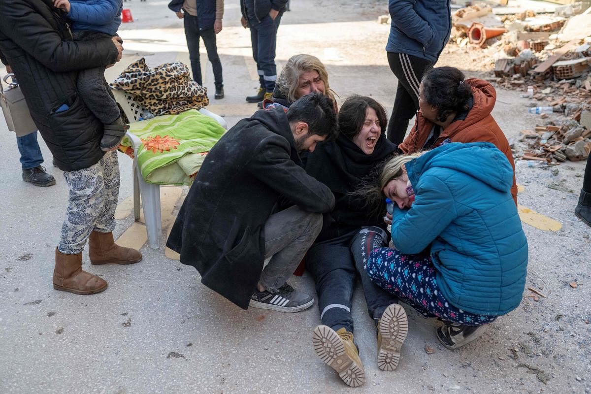 People react in mourning next to the rubble of collapsed buildings in Hatay, southeastern Turkey. Credit: AFP Photo
