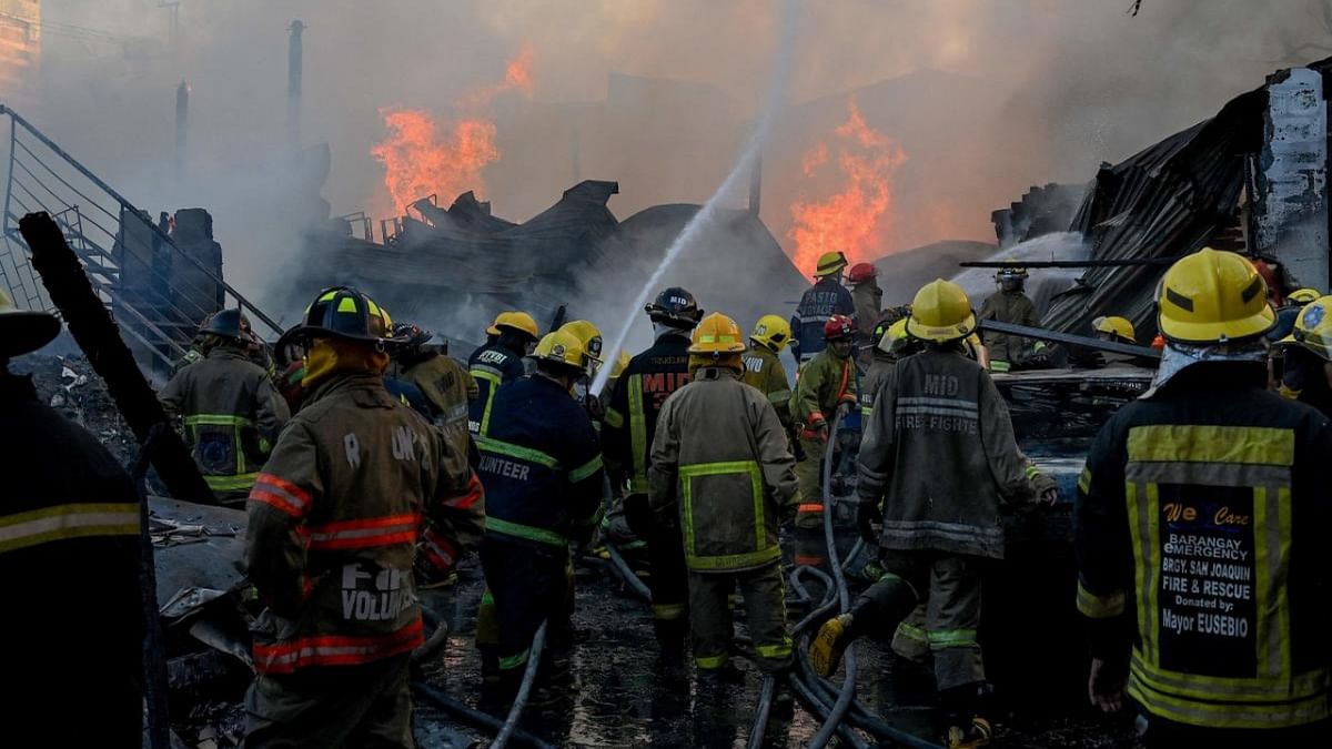 Firefighters work at the scene of a fire at a warehouse in the financial district of Makati, suburban Manila on February 10, 2023. Credit: AFP Photo
