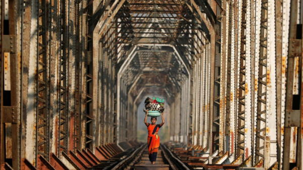 Woman carrying luggage walks along a railway track on the outskirts of Mumbai. Credit: Reuters Photo