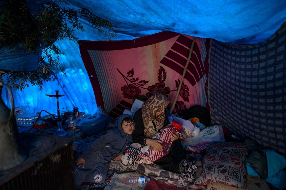 A Syrian women sit in a tent near on the wreckage of a road destroyed in Demirkopru, a small Turkish village now divided by a large crack following two back-to-back massive earthquakes in Hatay. Photo Credit: AFP Photo