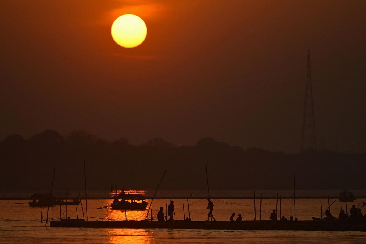 People are silhouetted against the setting sun along a riverbank at Sangam, the confluence of rivers Ganga, Yamuna, and mythical Saraswati in Prayagraj. Credit: Reuters Photo