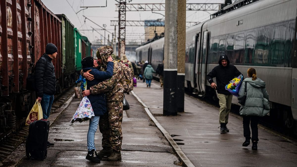 A Ukrainian serviceman embraces his wife as she arrives from Kyiv at the train station in Kramatorsk on February 26, 2023, amid the Russian invasion of Ukraine. Credit: AFP Photo