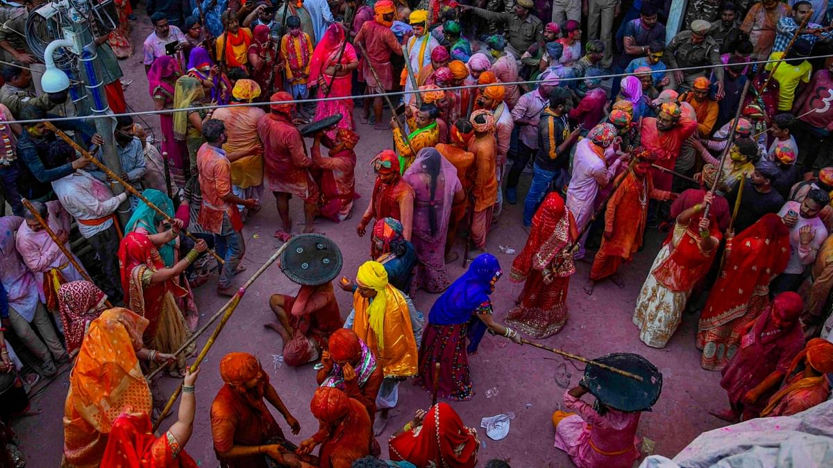 Holi in Barsana virtually is a repeat of Holi representing the 'Dwaapar' age with men trying to drench women with colours and women stopping them with baton attacks. Credit: PTI Photo