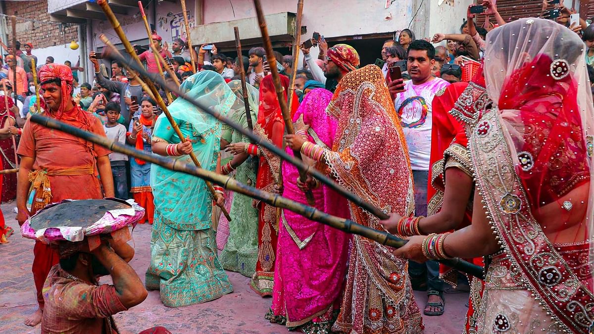 Legend has it that when Krishna visited Barsana to spray colours on his beloved, Radha and her friends ‘playfully’ hit him with sticks and drove him out of the town. Lathmar Holi seeks to recreate that. Credit: PTI Photo