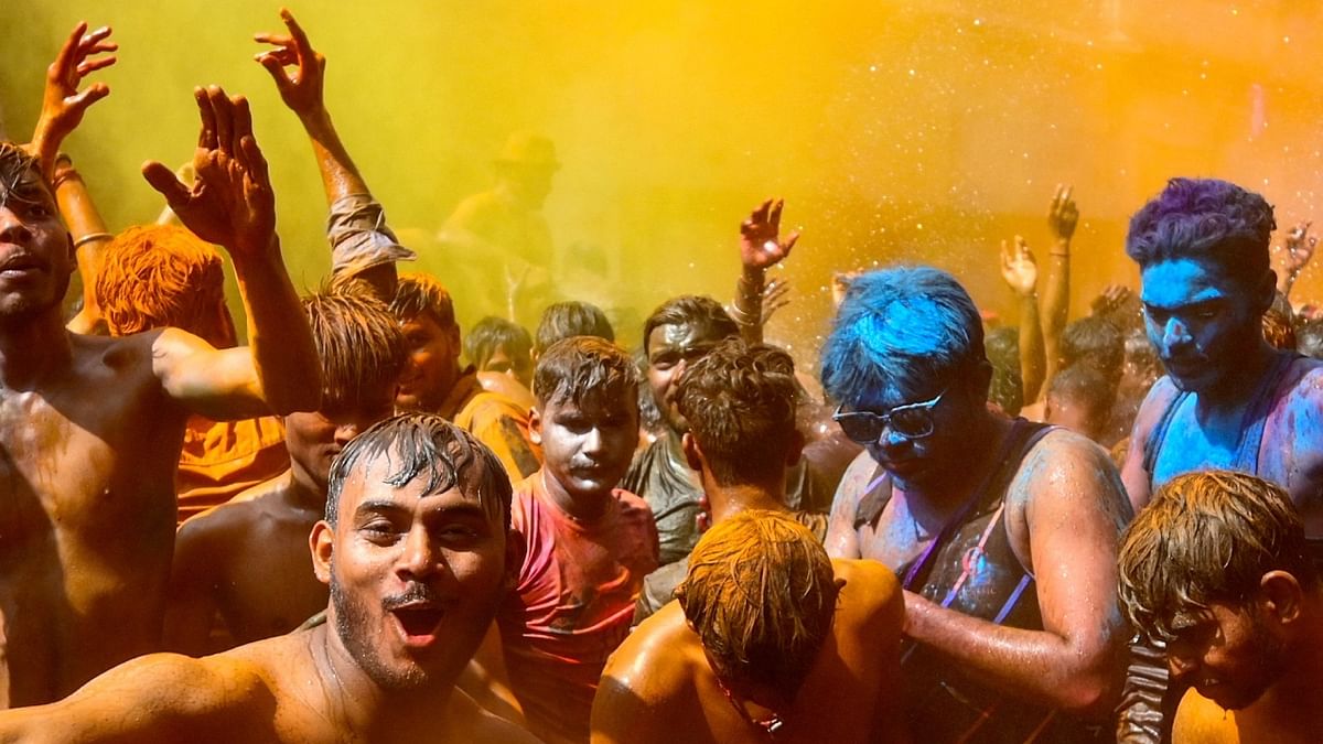 People daubed in colours dance as they celebrate Holi, the spring festival of colours, in Prayagraj. Credit: AFP Photo