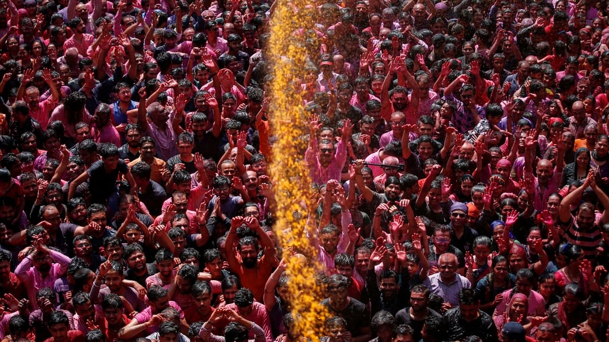 Devotees pray as they are sprayed with coloured water at a temple's premises, during Holi celebrations in Ahmedabad. Credit: Reuters Photo