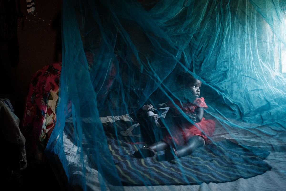 Ruth Kavere (L), 65, demonstrates to use a mosquito net with her granddaughter Faith, 3, who completed doses through the world’s first malaria vaccine (RTS, S) pilot program, at home in Mukuli. Credit: AFP Photo
