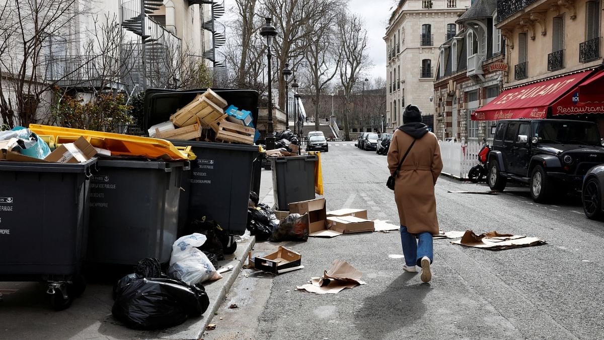 A person walks on a street where garbage cans are overflowing, Paris. The legislation will face a bumpy path through parliament and Macron's government may be forced to use special constitutional powers to bypass a parliamentary vote - something union leaders have warned him not to do. Credit: Reuters Photo