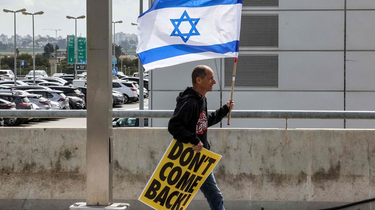 A demonstrator walks with an Israeli flag and a sign reading in English 'don't come back!'. Credit: AFP Photo