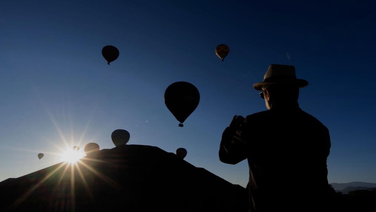 A man takes pictures of hot air balloons flying over the Pyramid of the Sun in Teotihuacan, Mexico State, during the spring equinox celebration on March 20. Credit: AFP Photo