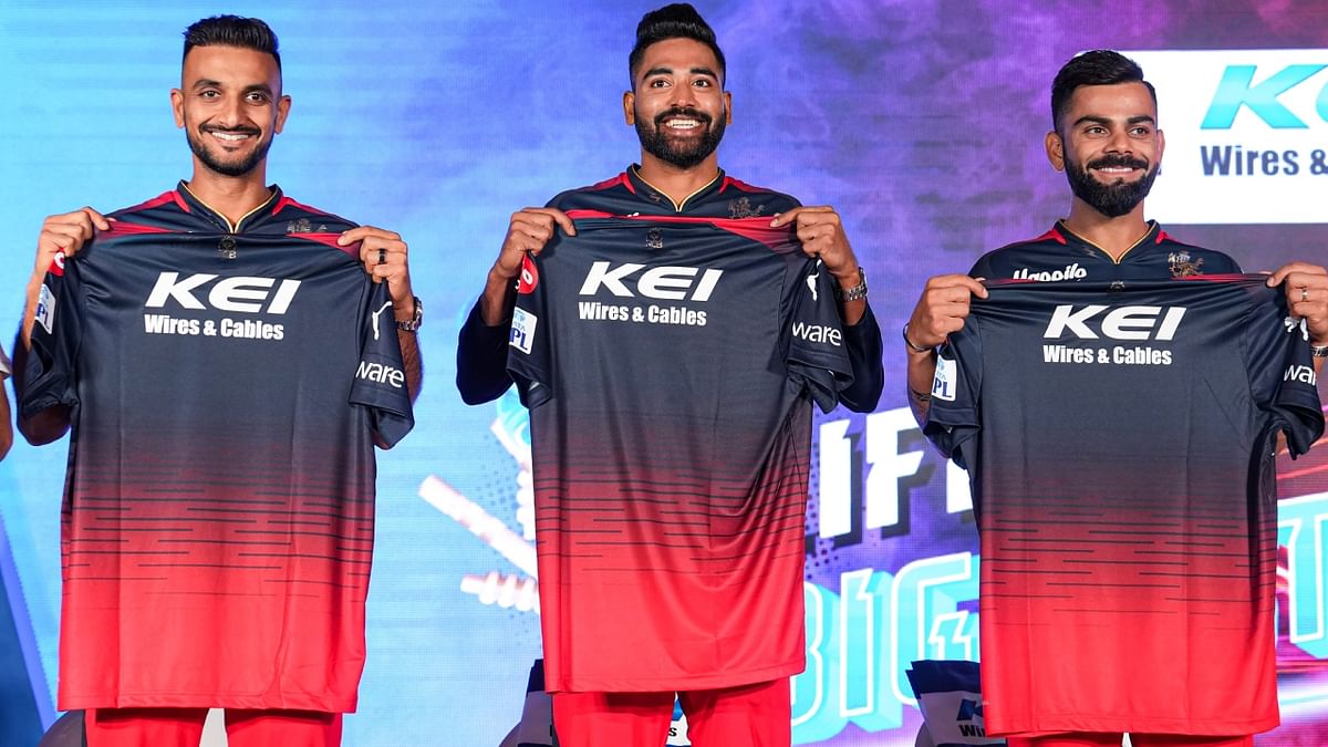 Royal Challengers Bangalore players Harshal Patel, Mohammed Siraj and Virat Kohli pose on the stage during the jersey launch event. Credit: PTI Photo