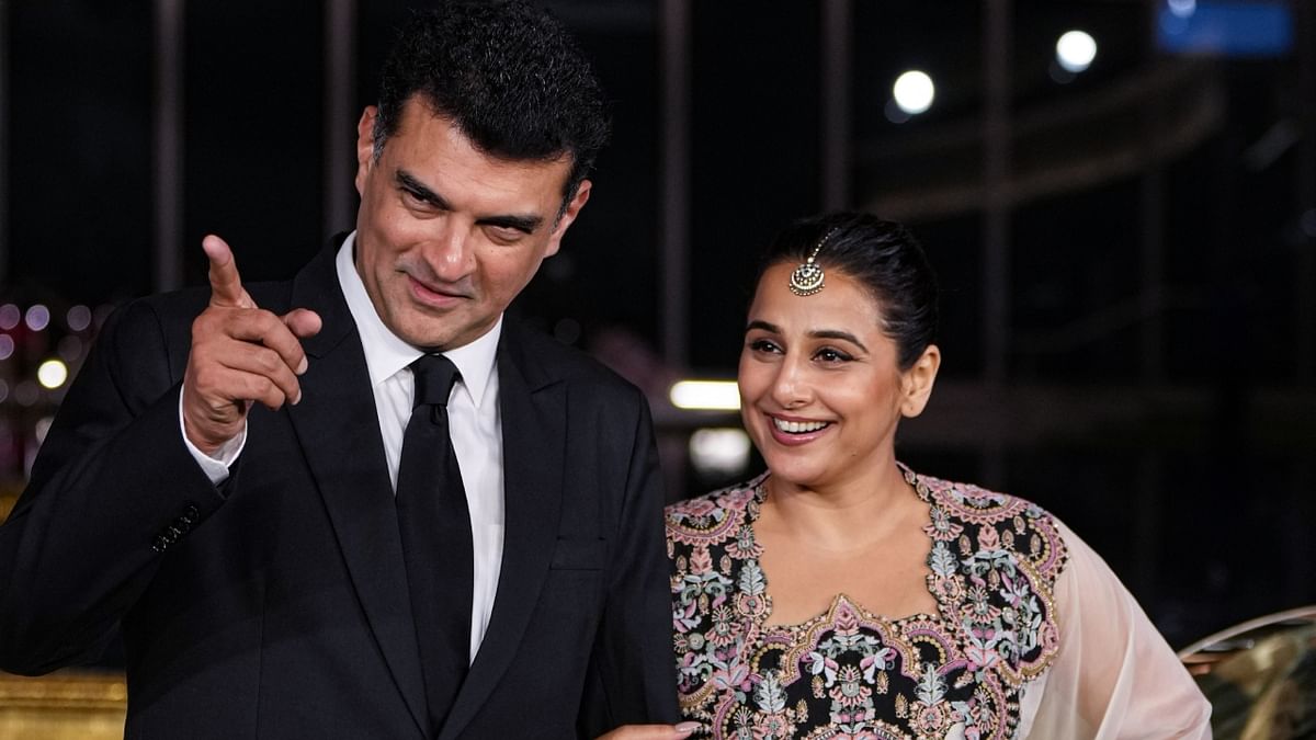 Siddharth Roy Kapur and Vidya Balan got clicked giggling as they try to attend to various cameras. Credit: PTI Photo