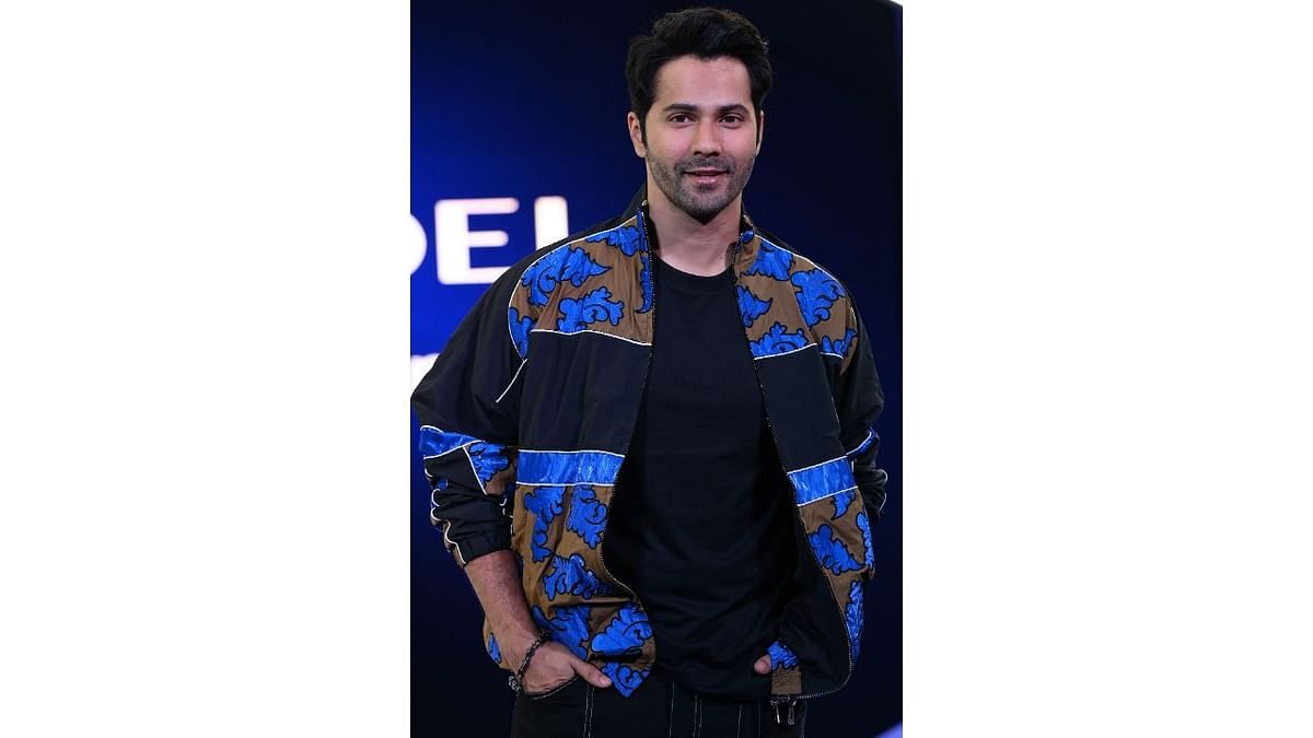 Varun Dhawan was spotted wearing a black t-shirt and black cargo pants paired with a funky jacket with shades of cobalt blue and sand. Credit: AFP Photo