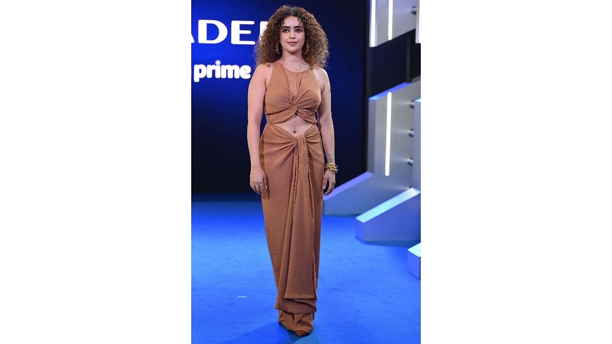 Sanya Malhotra was seen in a brown dress with flowing pleats and a belly slit. With her statement curls left untouched, the actor sure turned heads at the event. Credit: AFP Photo