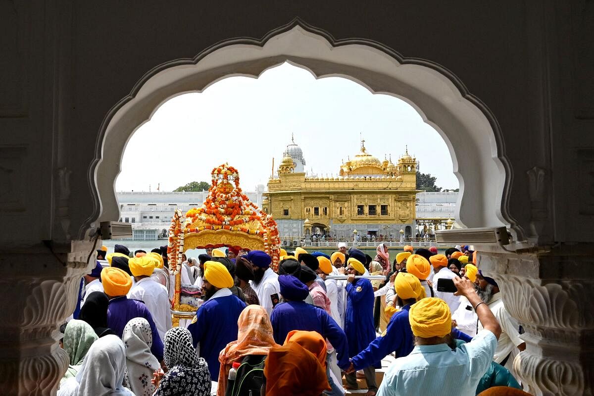 Sikh devotees carry the Guru Granth Sahib in a golden palanquin during a religious procession on the eve of the birth anniversary of the ninth Sikh Guru Teg Bahadur at the Golden Temple in Amritsar. Credit: AFP Photo