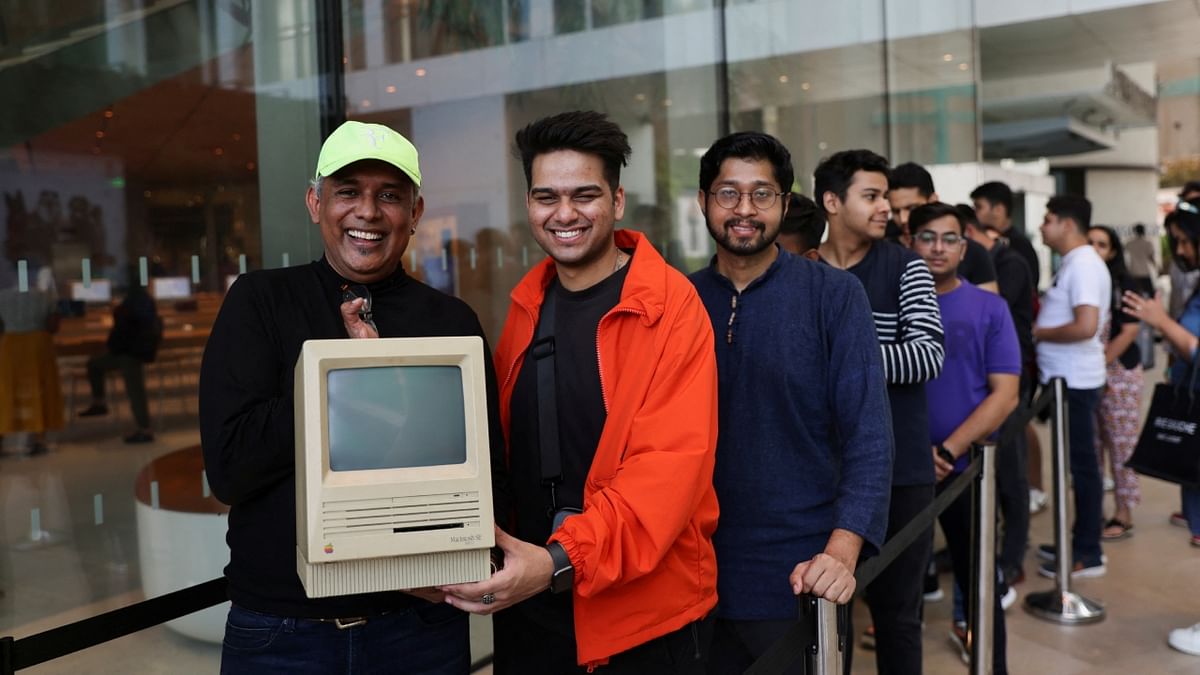 An Apple enthusiast poses with a Macintosh SE computer while waiting in a queue outside India's first Apple retail store, on the day of its opening in Mumbai. Credit: Reuters Photo