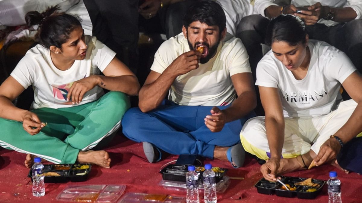 Wrestlers Bajrang Punia, Vinesh Phogat and others have dinner during their protest at Jantar Mantar, in New Delhi. Credit: PTI Photo