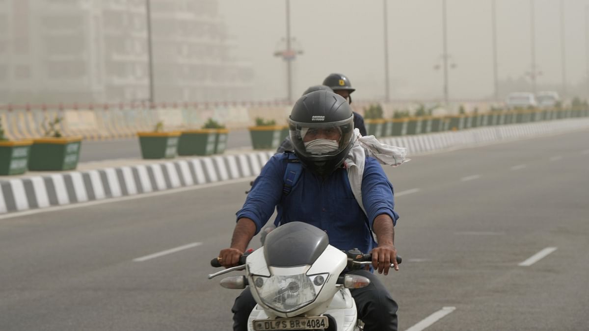 A man protecting himself from dust rides his scooter as the air quality deteriorates, in New Delhi. Credit: PTI Photo
