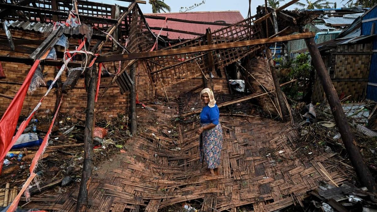A Rohingya woman stands in her destroyed house at Basara refugee camp in Sittwe on May 16, 2023, after cyclone Mocha made a landfall. The death toll in cyclone-hit Myanmar's Rakhine state rose to at least 41 on May 16, 2023, local leaders told AFP. Credit: AFP Photo