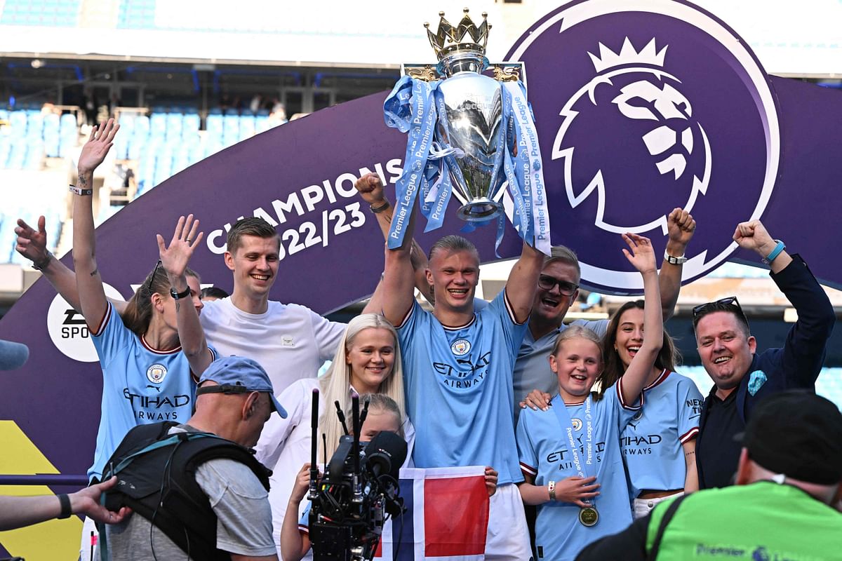 Manchester City's Norwegian striker Erling Haaland (C) lifts up the Premier League trophy as he celebrates with his family after the presentation ceremony following the English Premier League football match between Manchester City and Chelsea at the Etihad Stadium in Manchester. Credit: AFP Photo