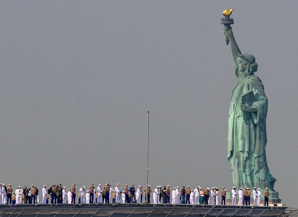 US Sailors and Marines stand on the flight deck of the USS Bataan, a Wasp-class amphibious assault ship, as it passes the Statue of Liberty during Fleet Week in New York Harbor. Credit: AFP Photo