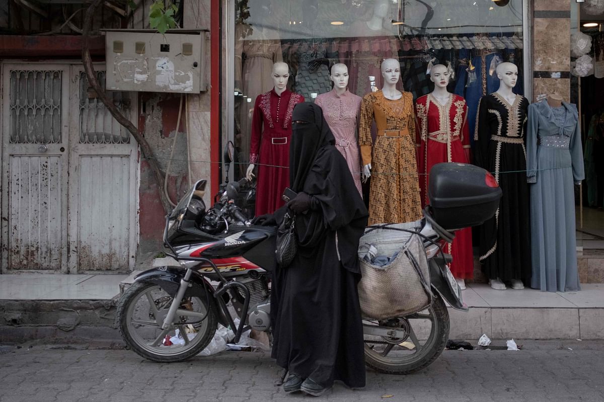 A Syrian woman wearing a niqab leans on a motorcycle in the Kocavezir neighborhood of Adana, in southern Turkey, which hosts a large number of Syrian refugees who fled the civil war, on May 25, 2023. Credit: AFP Photo
