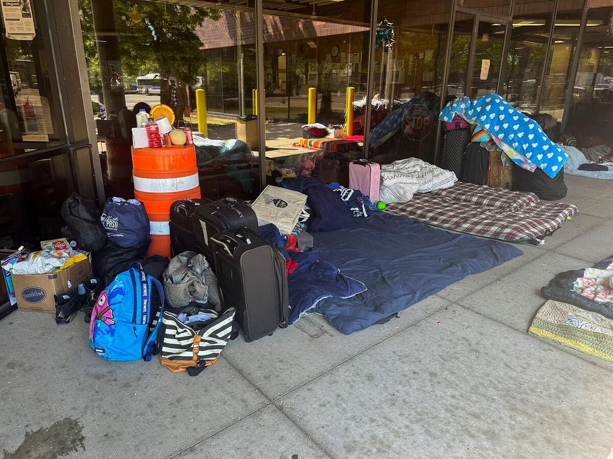 Makeshift beds and other belongings of migrants are laid on the ground outside a police station in Chicago. Credit: Reuters Photo