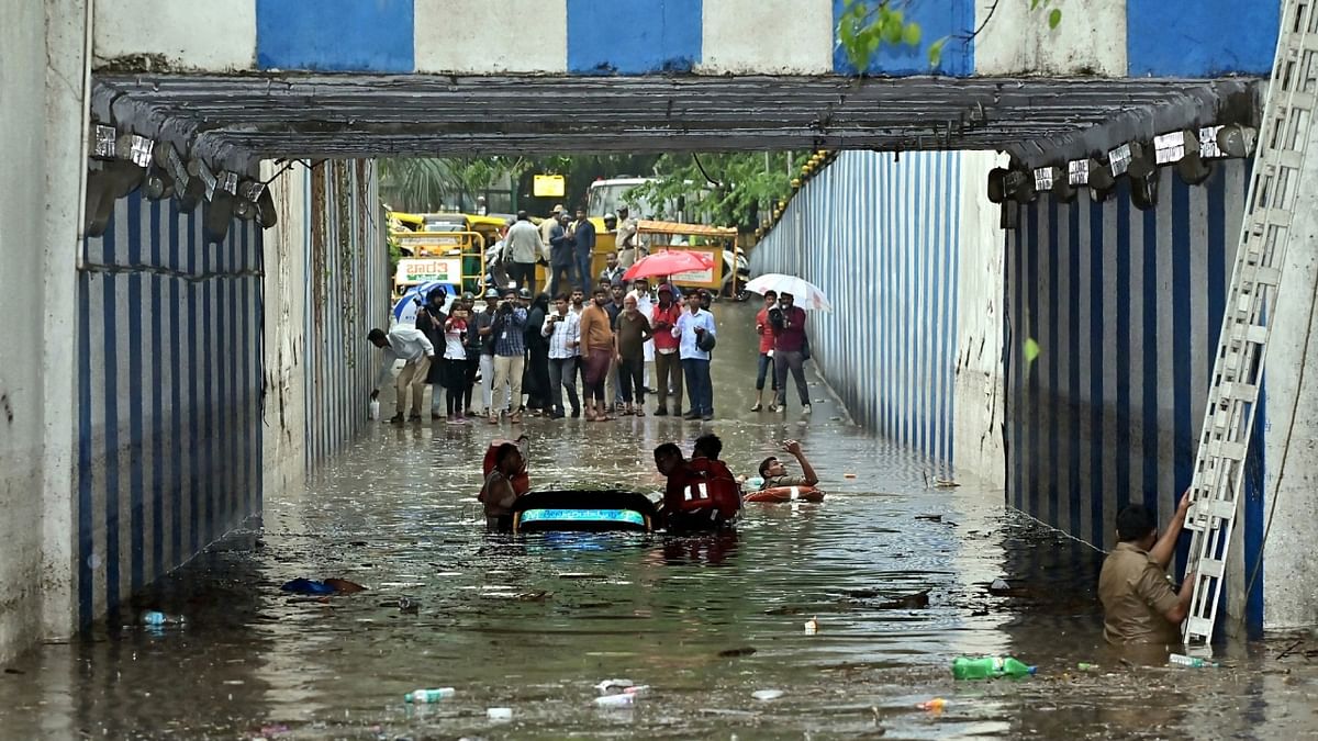 A rescue operation undertaken after an auto-rickshaw gets submerged on a waterlogged street due to heavy rainfall in Bengaluru. Credit: PTI Photo
