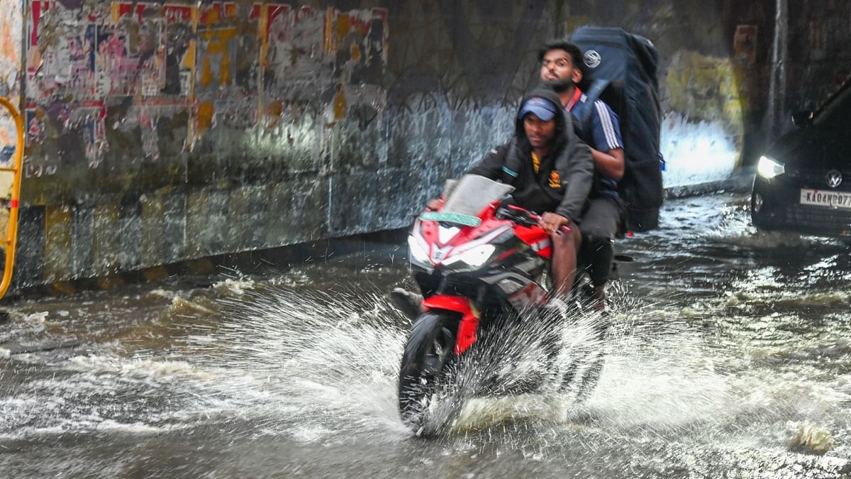 A motorist wades through a flooded road at Seshadripuram underpass, Hari Krishna Road in Bengaluru. Credit: SK Dinesh/DH Photo