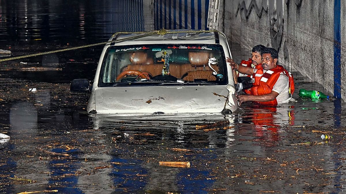 Rescue operation undertaken after a car got stuck in a waterlogged underpass following heavy rain, in Bengaluru. Credit: PTI Photo